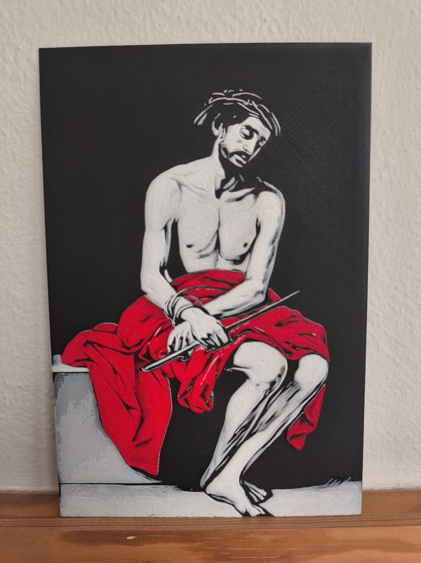 Réplica táctil en relieve impresa en 3D: un hombre sentado con corona de espinas y la cabeza inclinada, las manos atadas sosteniendo una vara y un manto rojo sobre las piernas, en blanco, gris y rojo sobre fondo negro.